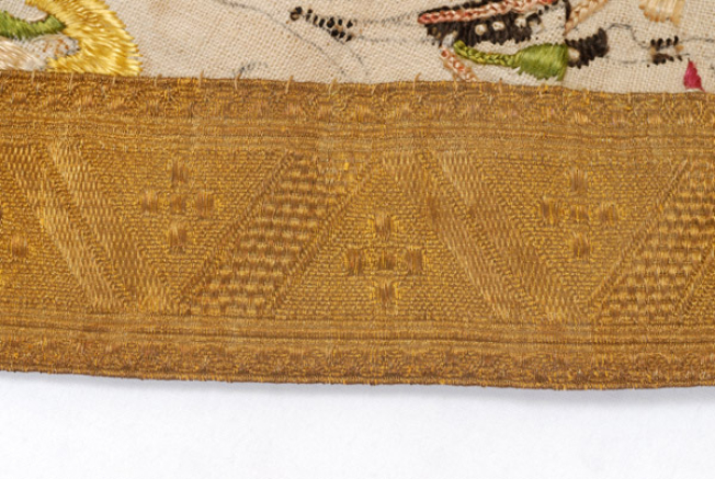 Detail of the applique decoration, gold chevron with embellished crooked line and crosslets.