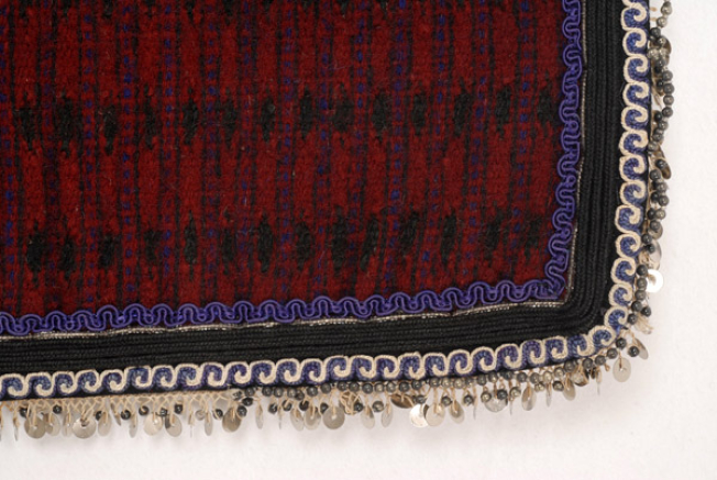 Selvages of the apron, detail of the applique decoration with braid in curve-shaped motifs, beads, cordons and felt pieces with a double spiral meander 