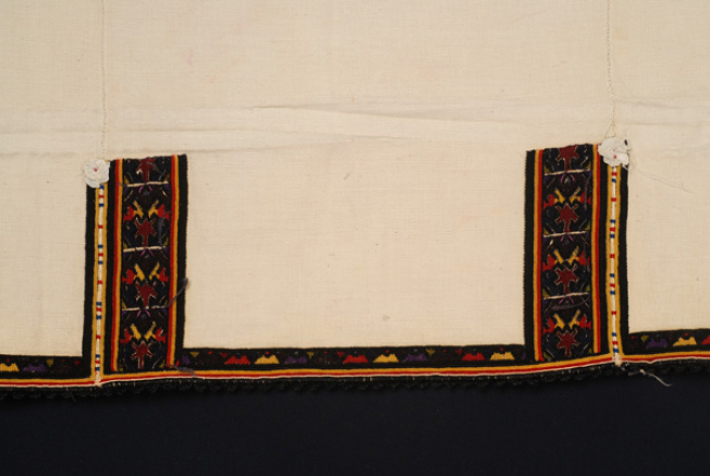 Border (panel of the back), detail of the decoration of the seam with two columns with stylized motifs, crafted with woollen coloured threads and silver thread 