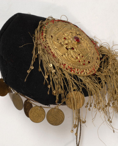 Small felt tarbush with gold fringes. The applique decoration consists of a gilded metal dish with embossed decoration