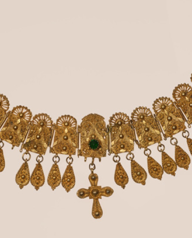 Gilt yordani, shapely pectoral ornament, featuring a pointiller design and decorated with a green glass stone
