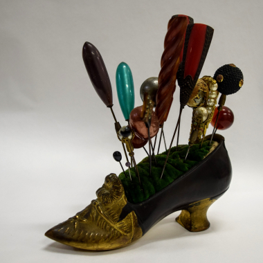 Hat pins on a “cushion” placed on a base in the shape of a woman’s high-heeled shoe. CMLE, Accession No. 16482/1-20. Donated by Era Lambria. Photo: Hara Dendia.