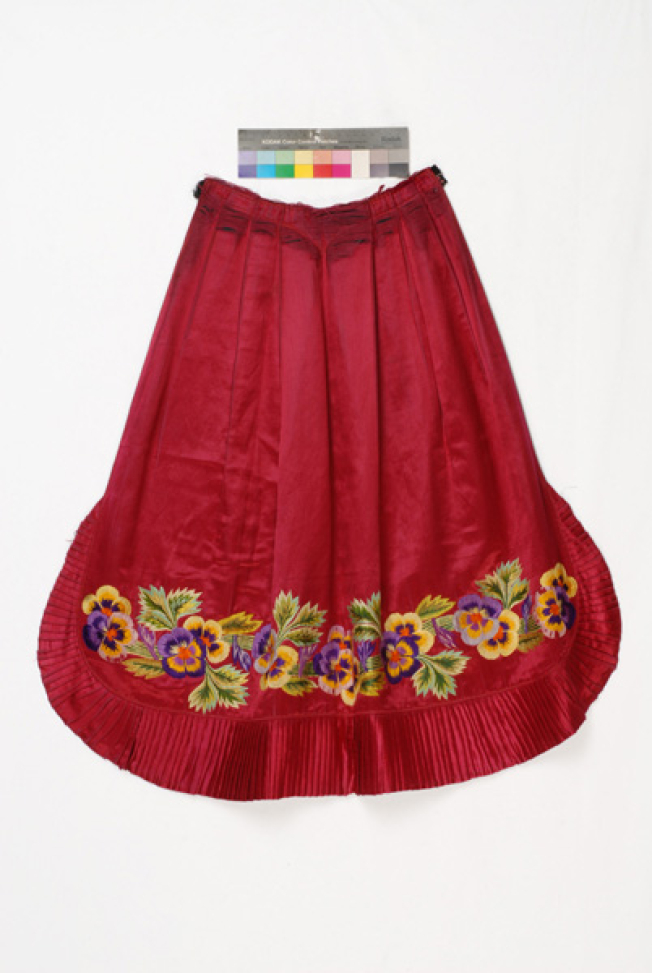 Bottom of the apron, detail of the decoration with multicoloured pansies, crafted with raised stitch