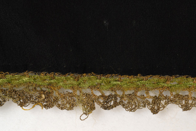 Detail of the applique decoration with gold lace crafted with the embroidery needle and tracks of green silk thread