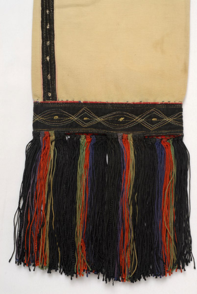 Sleeve, detail of the decoration with cotton fabric with three-coloured threads. Finishing with silk coloured over tassels
