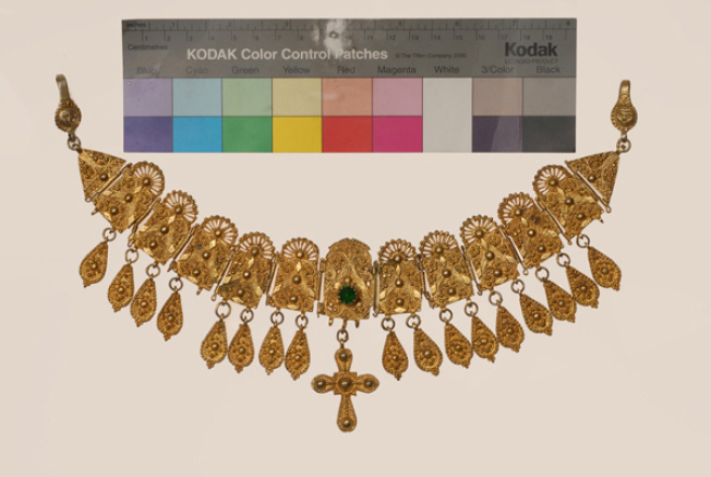 Gilt yordani, shapely pectoral ornament, featuring a pointiller design and decorated with a green glass stone