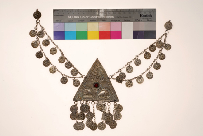 Silver forged triangle ornamente with an embossed decoration and metal grainy pendants