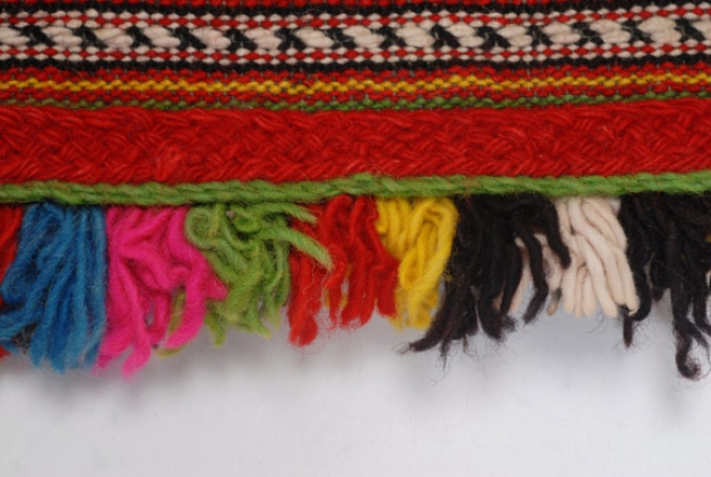 Detail of the decoration, applique woolgaitani (cordon), wool cord, and small fringes made of fullen wool fabric at the edging