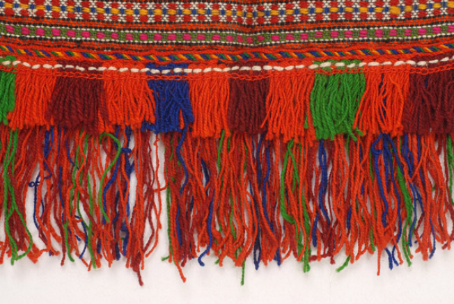 Edge of the apron with a double row of coloured woollen fringes 