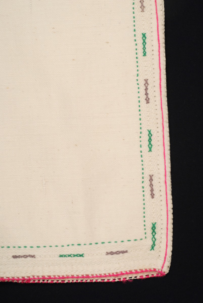 Sleeve, detail of the seam with coloured embroideries crafted with cross-stitch 