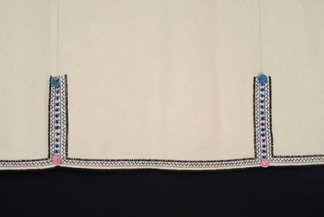 Border, detail of the lacy band of the seam, the embroidered and applique decoration with coloured rosettes