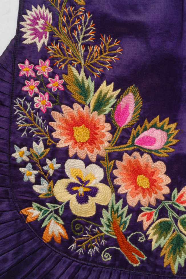 Bottom of the apron, detail of the decoration with multicoloured vegetal motifs, crafted with various stitches (riza (stem stitch), light stitch, rococo stitch) 