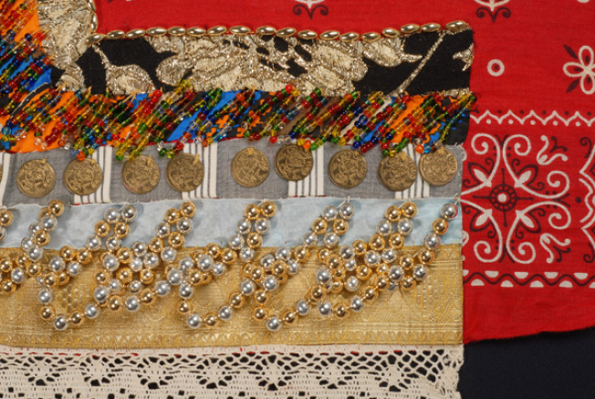 Detail of the applique decoration with industrial fillets, plain coloured and multicoloured ribbons, gilded coins and shiny beads