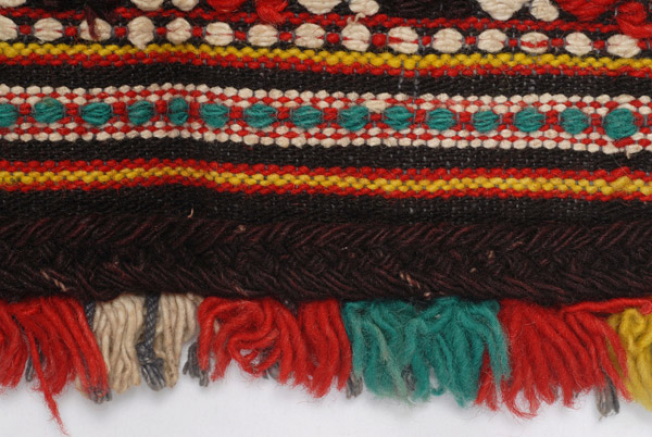Detail of the decoration, applique woolgaitani and small polychrome fringes made of fullen wool fabric at the edging 