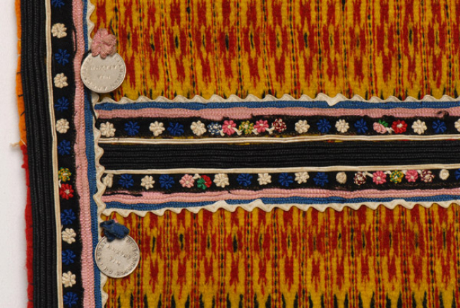 Επίρραπτη διακόσμηση με γαϊτάνι μεταξωτό, κορδέλες, νομίσματα και τσόχινα κομμάτια κεντημένα με μικρά χρωματιστά άνθη