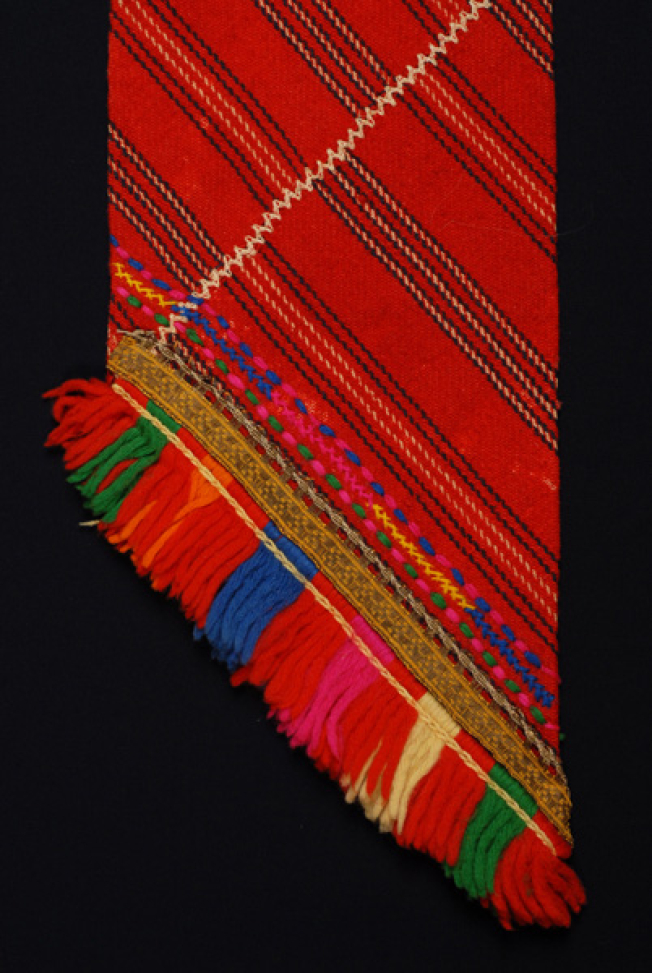 Detail of the embellished decoration (mannes) and embroidered joint. The sash edge is decorated with embroidery, applique fillet and fringed ends.