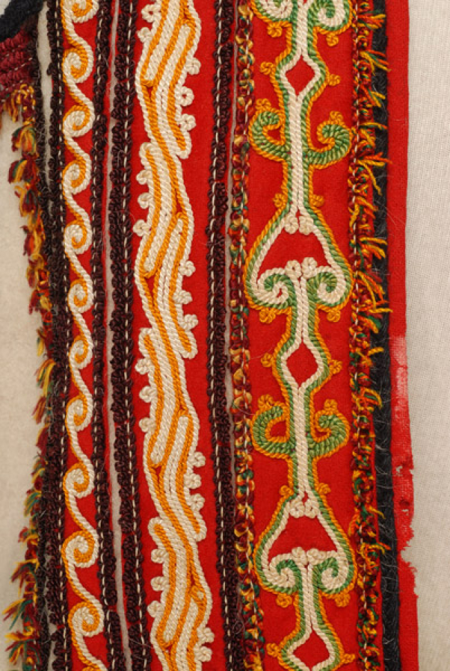 Front panel, detail of the decoration with vertical embroidered bands