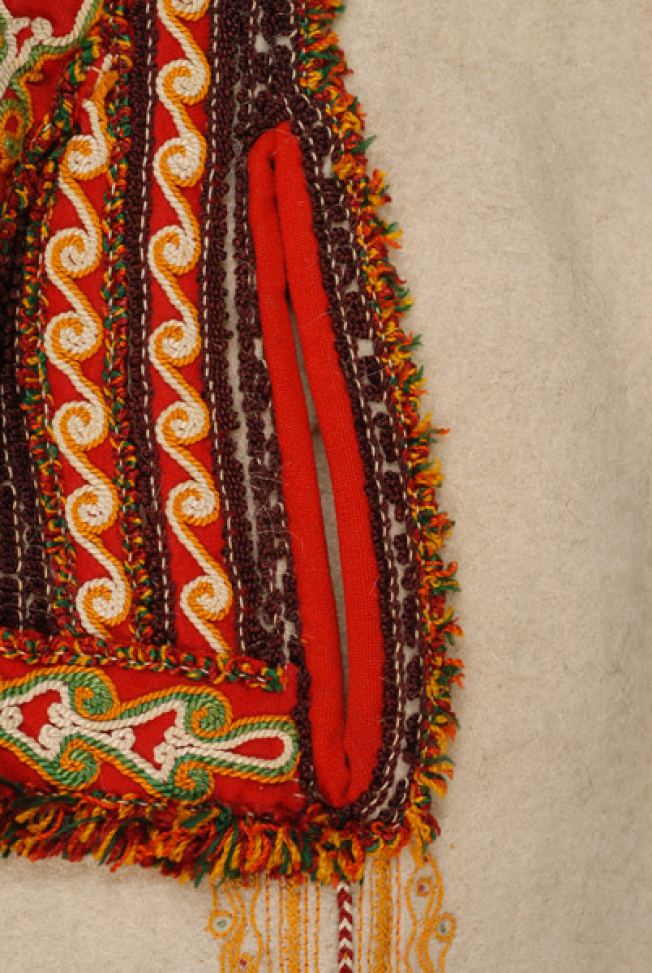 Side, pocket decorated with dark coloured wool cordon