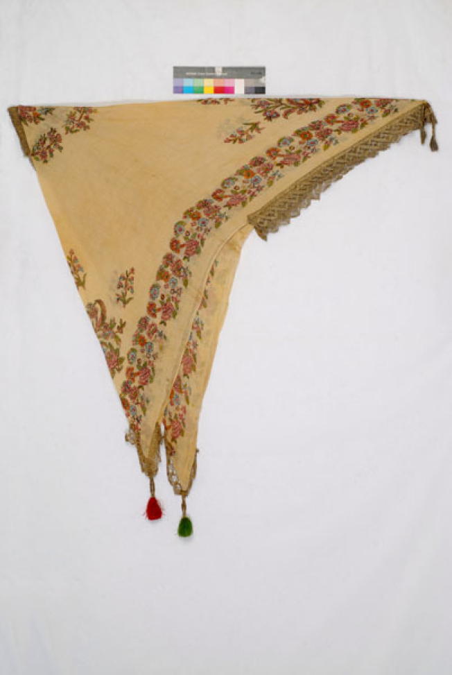 Printed yellow cotton head kerchief with leafy scrolls and flowers. Applique decoration with gold lace and colourful silk tassels