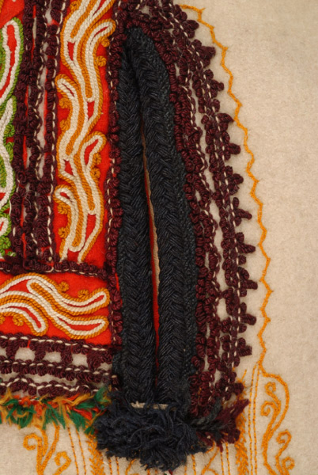 Side, pocket decorated with dark coloured wool cordon