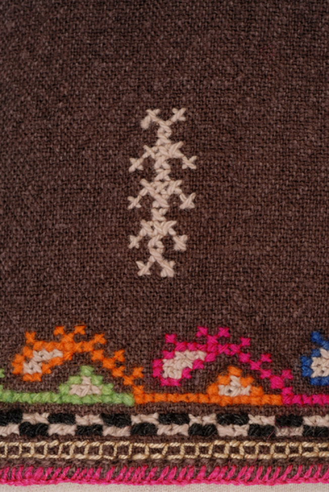 Detail of the decoration at the border: embroidery at the hem and stylized motifs with cross-stitch