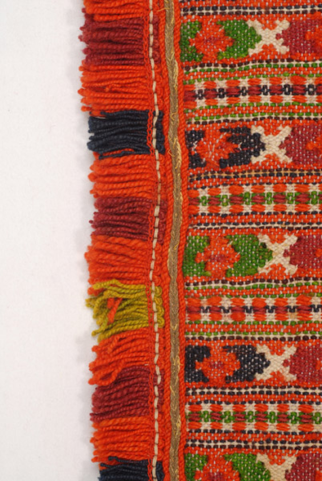 Edge of the apron, detail of the applique decoration with gold cordon and coloured woollen fringes 