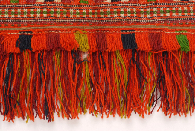 Edge of the apron with a double of coloured woollen fringes