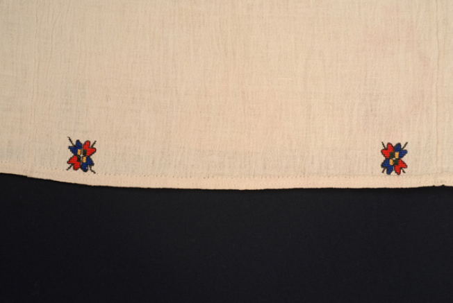Detail of the embroidered decoration with floral motifs at the border, at the straight front panel