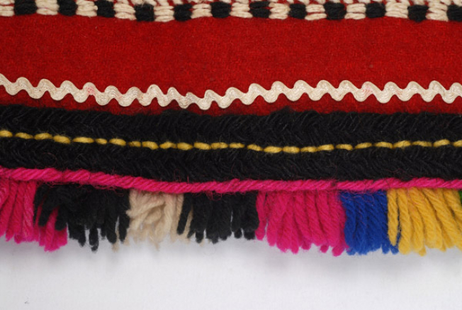 Detail of the decoration, applique braid, wool gaitani (cordon), wool cord, small fringes and polychrome tassels made of fullen wool fabric at the edge
