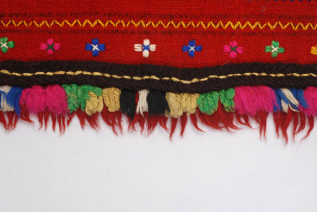 Detail of the decoration, applique wool gaitani (cordon), tassels and small fringes made of fullen wool fabric at the edge 