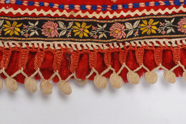 Detail of the decoration, applique cord, fillet commercially available and lace crafted with the embroidery needle which forms netting with small balls at the edge of the apron. The small fringes made of sayiaki (fullen wool fabric) are traced underneath
