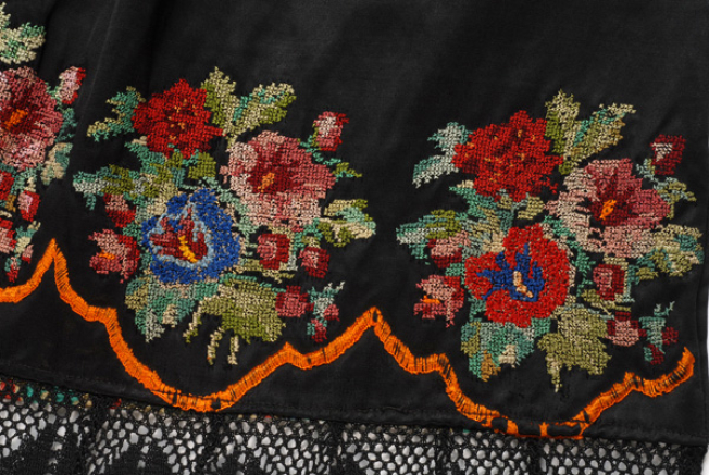 Bottom of the apron, detail of the decoration with multicoloured flower bouquets, crafted with double cross-stitch
