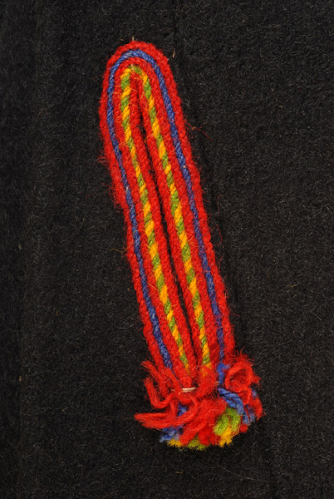 Δεξί μπροστινό φύλλο, κατακόρυφο άνοιγμα (τσέπη), στολισμένο ολόγυρα με χρωματιστά μάλλινα στρίμματα 
