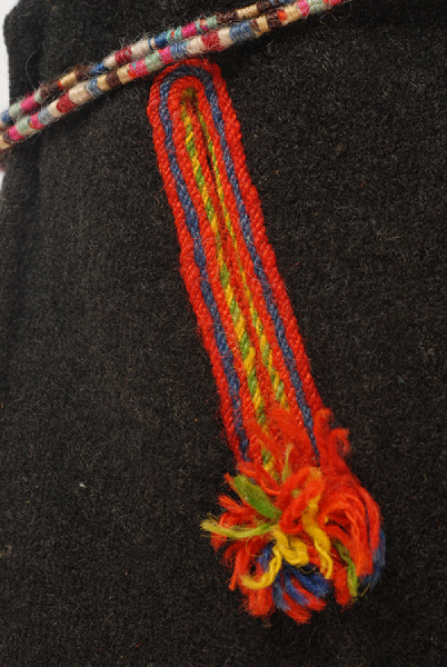 Δεξί μπροστινό φύλλο, κατακόρυφο άνοιγμα (τσέπη), στολισμένο ολόγυρα με χρωματιστά μάλλινα στρίμματα 