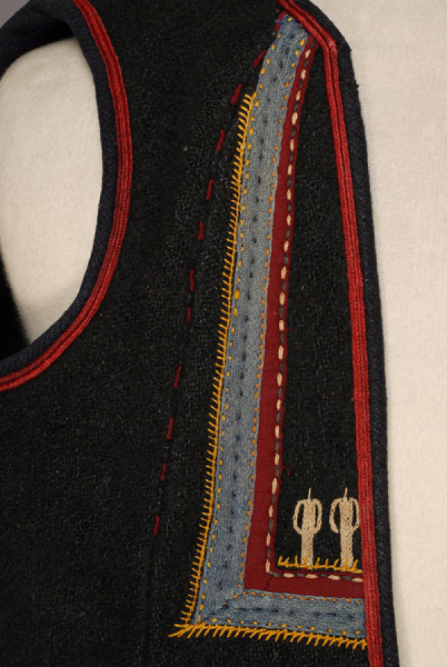 Detail of the decoration at the chest: specular right triangles made of applique elements with embroidery at the bottom