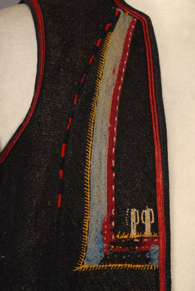 Detail of the decoration at the chest: specular right triangles made of applique elements with embroidery at the bottom