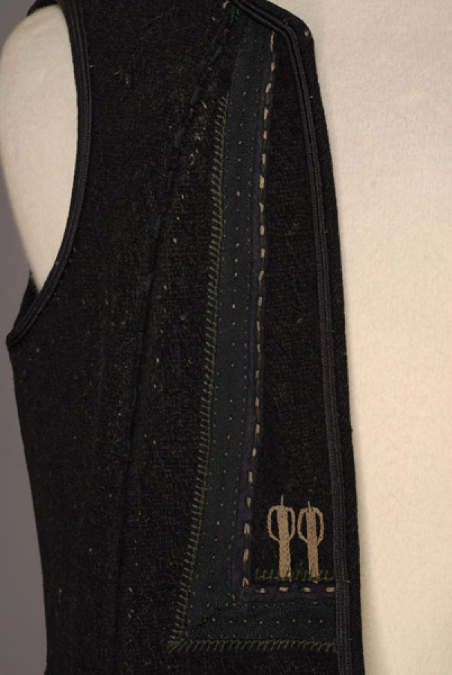 Detail of the decoration at the chest: specular right trianges made of applique elements with embroidery at the bottom