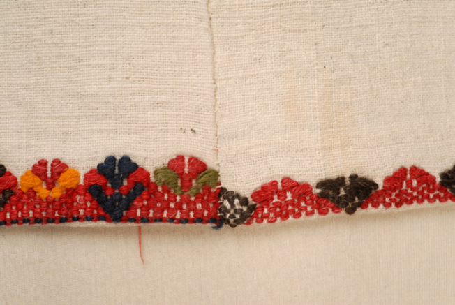 Detail of the embroidered decoration at the border with two different band-like motifs, as it can be seen at the joint of the front and side panels