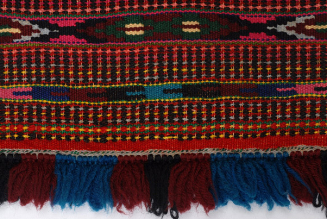 Detail of the embellished decoration at the bottom of the apron and its fringed end.