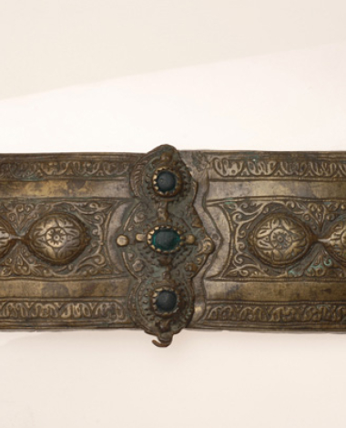 Hammered gilt buckle with embossed decoration, adorned with green glass stones