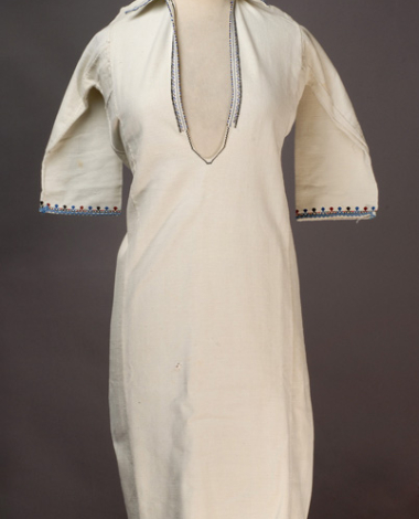 White cotton woven chemise, ornamented with blue and black beads and with multicoloured embroideries at the hem of the sleeves